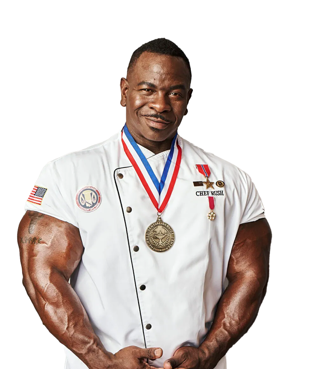 Chef Andre Rush in chef's whites, medals across his chest, arms crossed